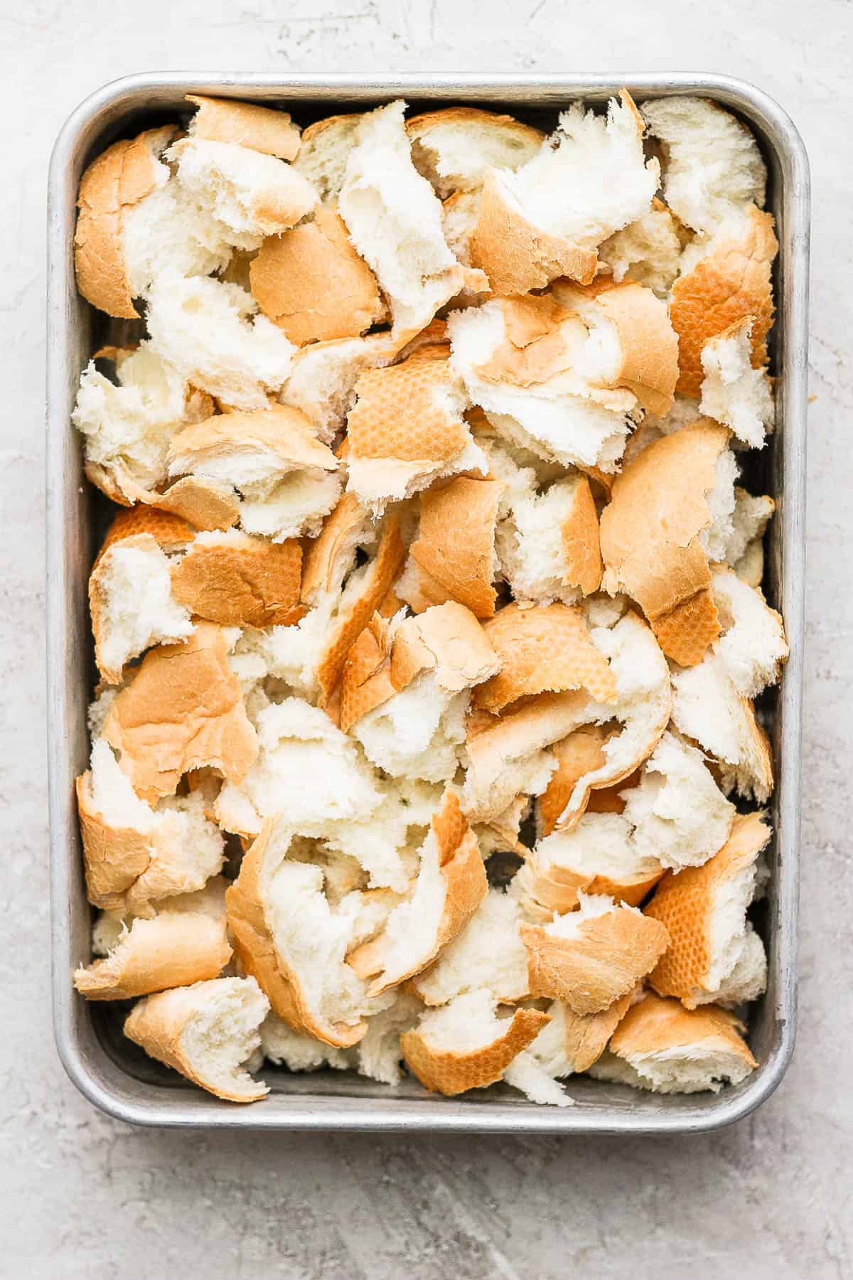 A 9x13 baking pan with chunks of french bread in it.