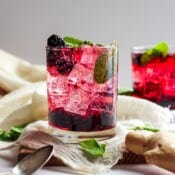 A glass of blackberry ginger smash spritzer with another glass in the background.