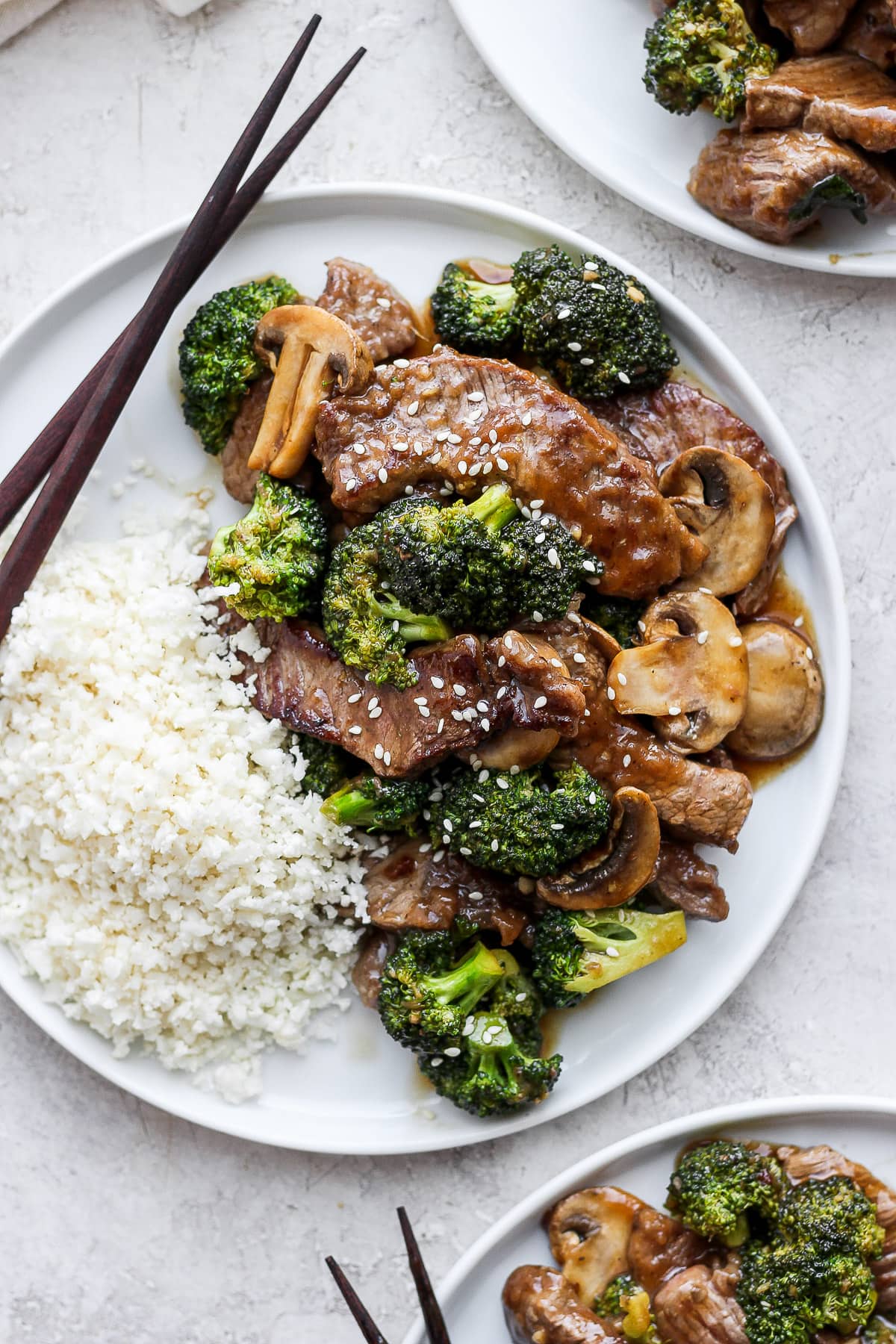 Plate of healthy beef and broccoli with cauliflower rice and chopsticks. 