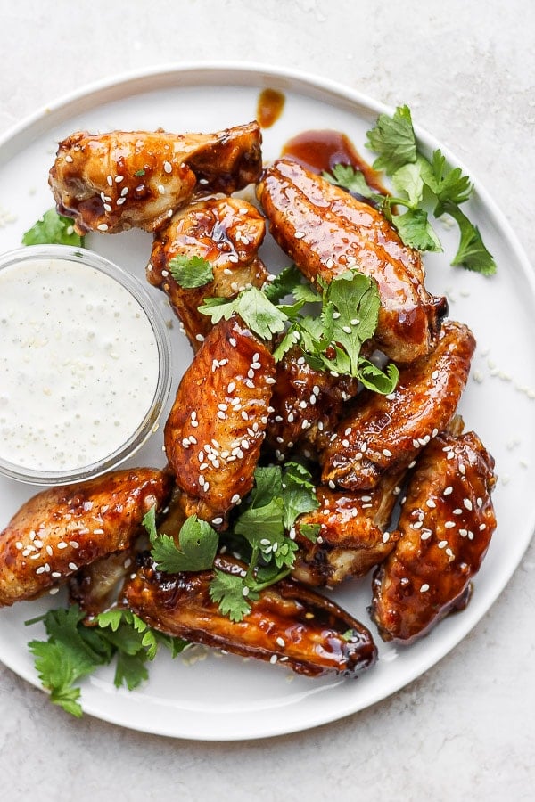 Plate of ginger sesame wings with fresh cilantro and a bowl of homemade ranch dressing. 