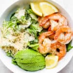 Bowl of shrimp caesar salad with avocado.