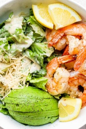 Bowl of shrimp caesar salad with avocado.