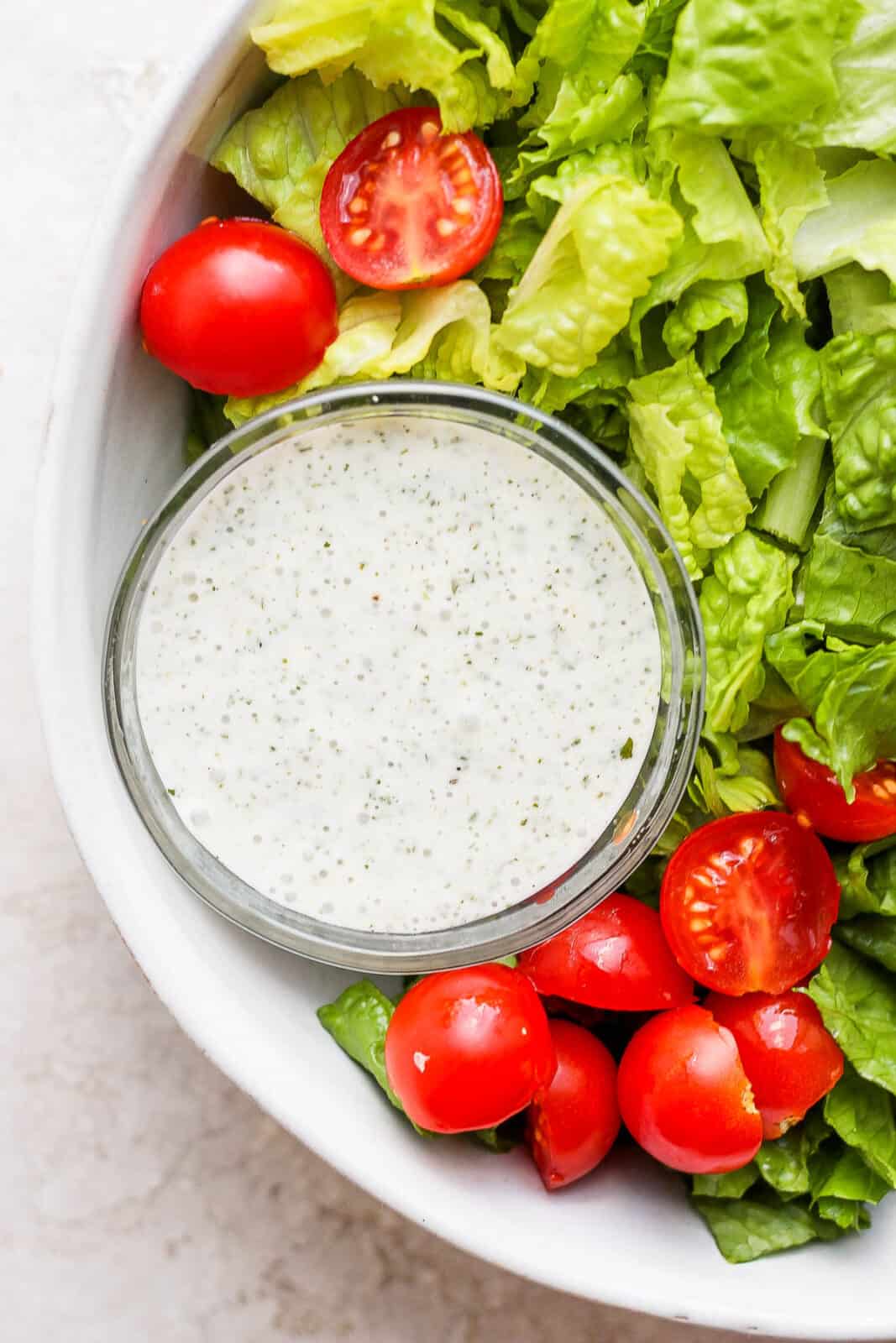 Bowl of lettuce with cherry tomatoes and dairy free ranch dressing.