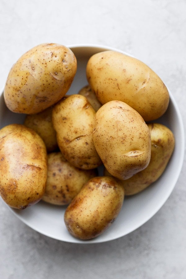 Clean yukon gold potatoes in a white bowl.