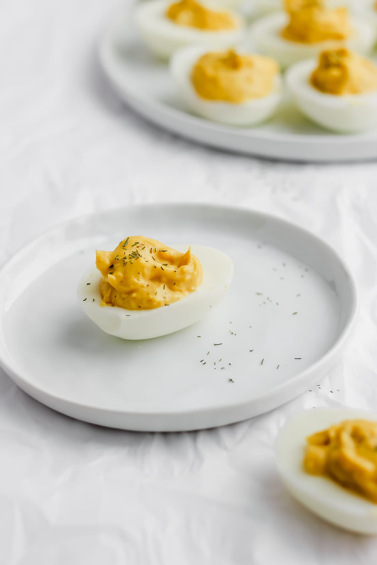 A garnished deviled egg on a white plate.