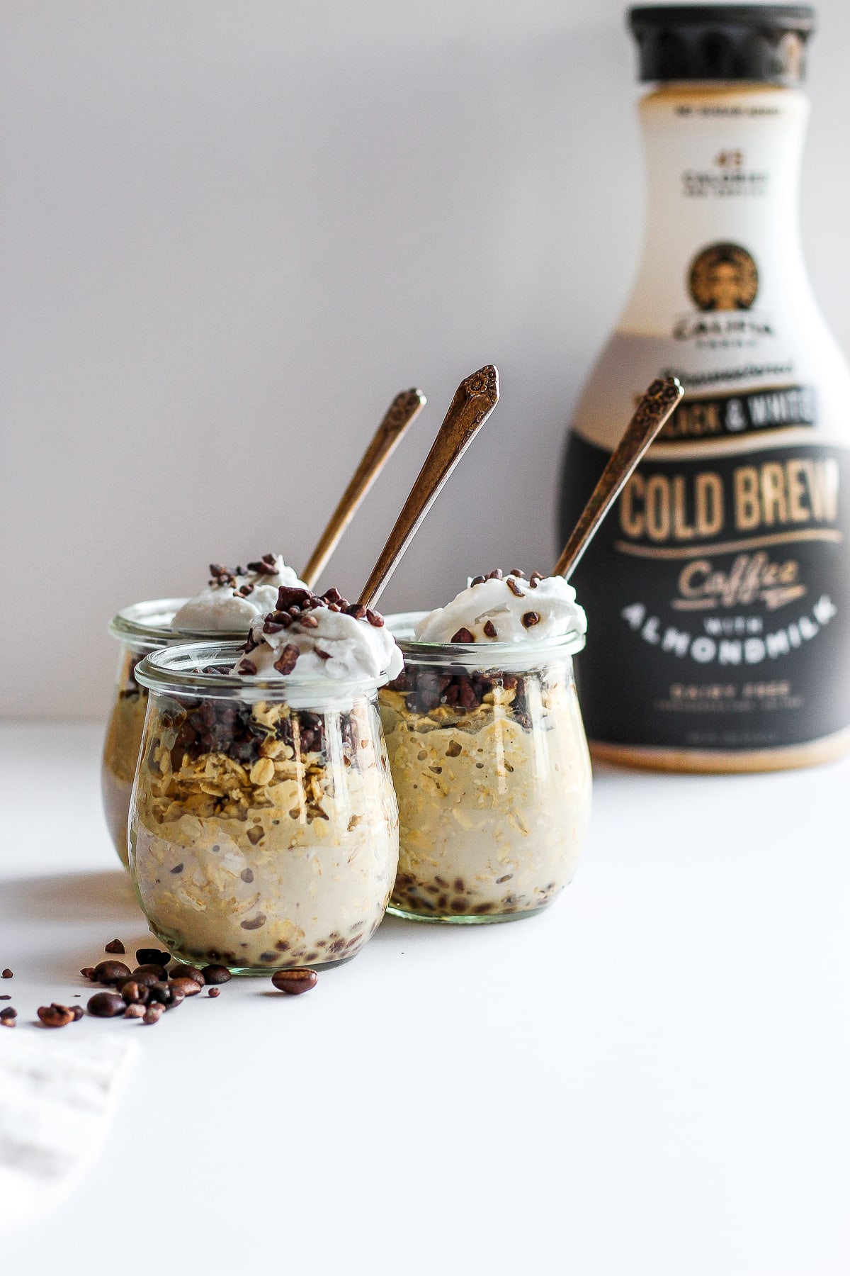 Three jars of cold brew overnight oats with a container of Califia Farms cold brew coffee in the background.