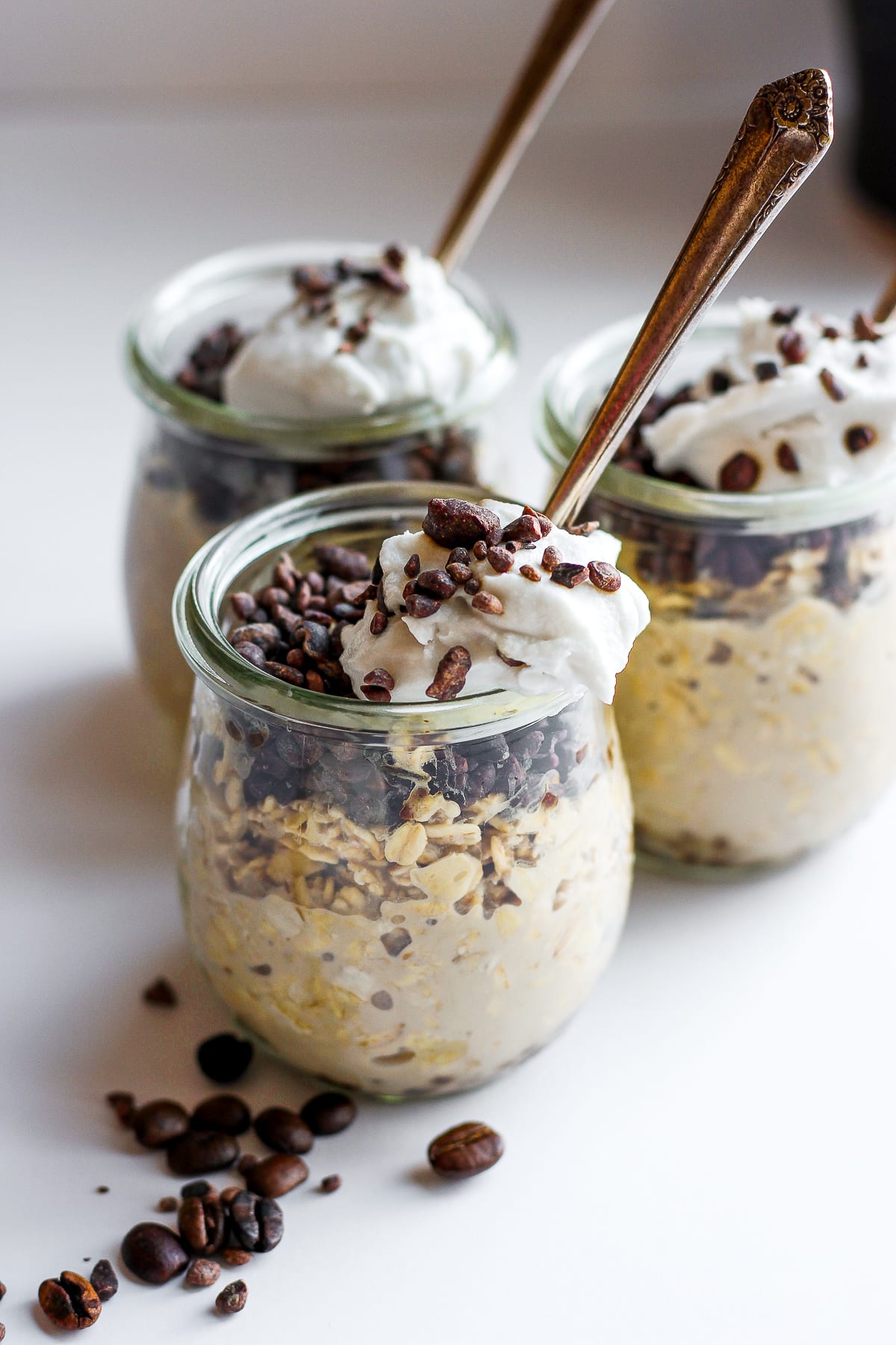 Three small jars of cold brew overnight oats with toppings and spoons.