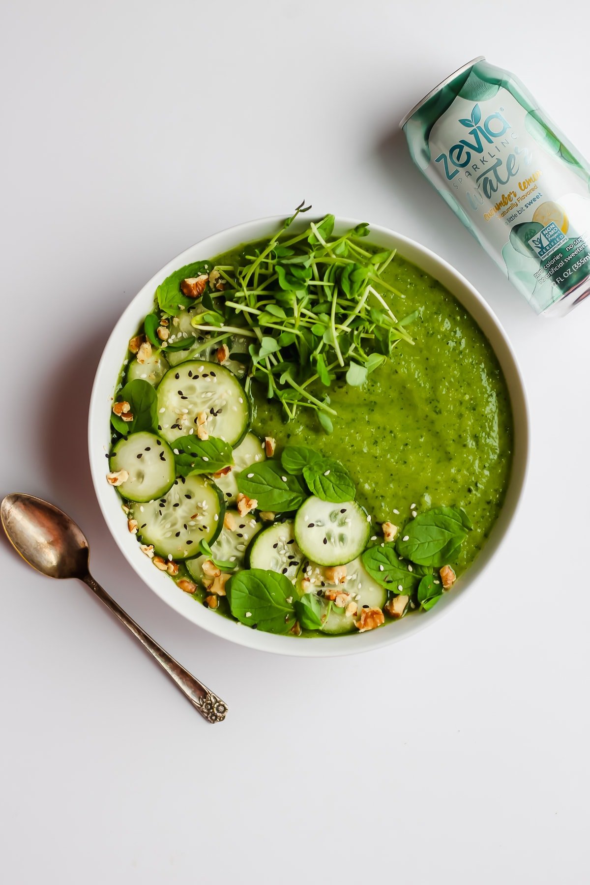 A healthy green smoothie bowl with a spoon next to it.