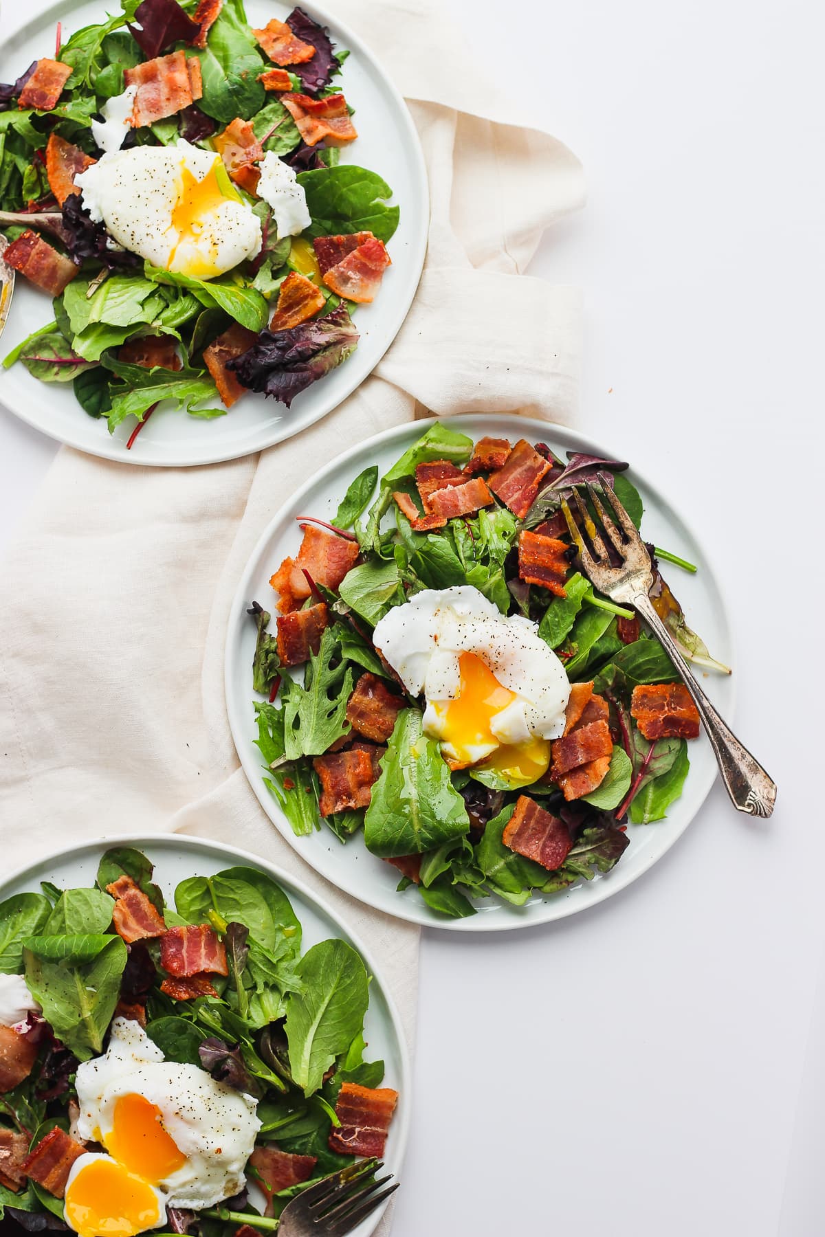 Two breakfast salads on white plates with a fork.