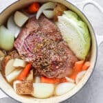 A Dutch Oven filled with cooked corned beef and cabbage.