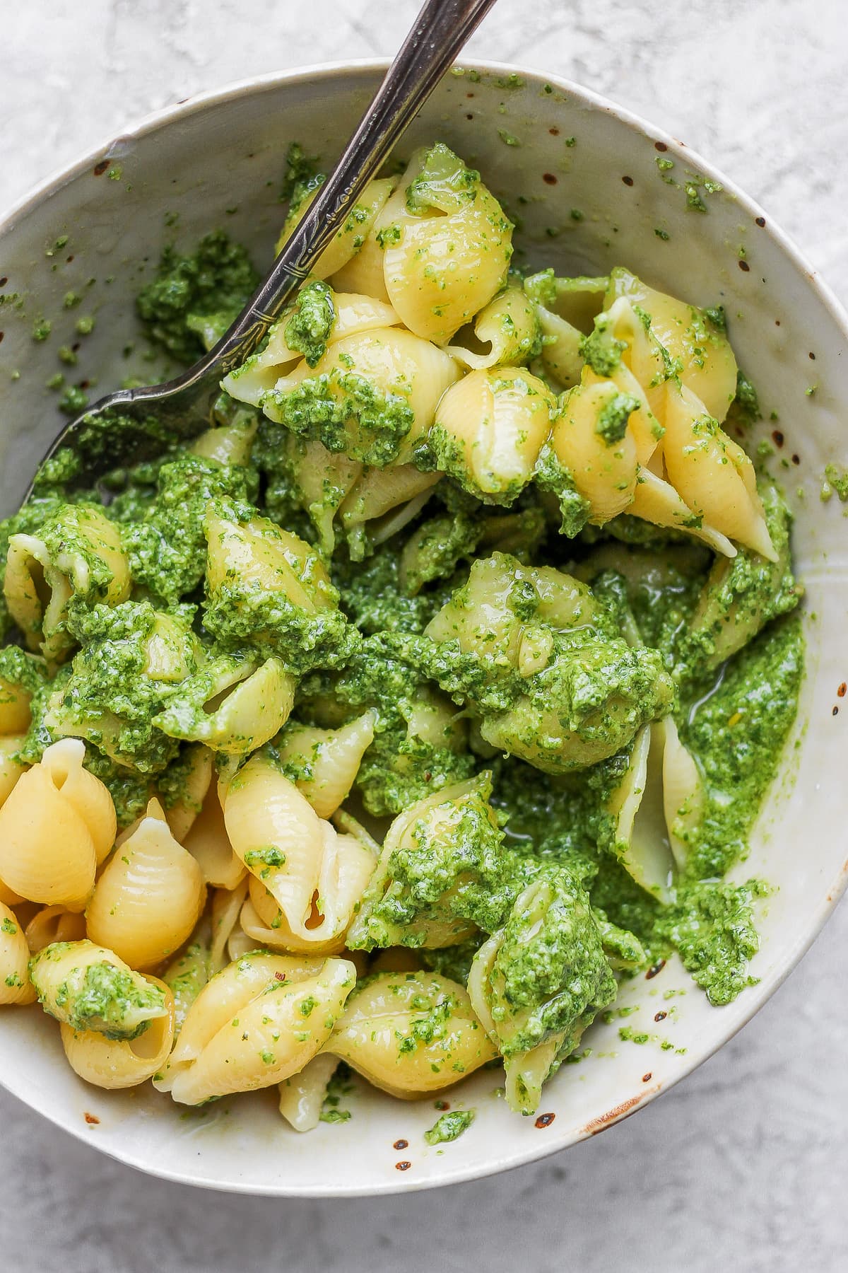 Bowl of cooked pasta shells with vegan pesto. 