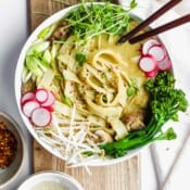 Vegan sweet green curried noodles in a white bowl with chopsticks sticking out the side.