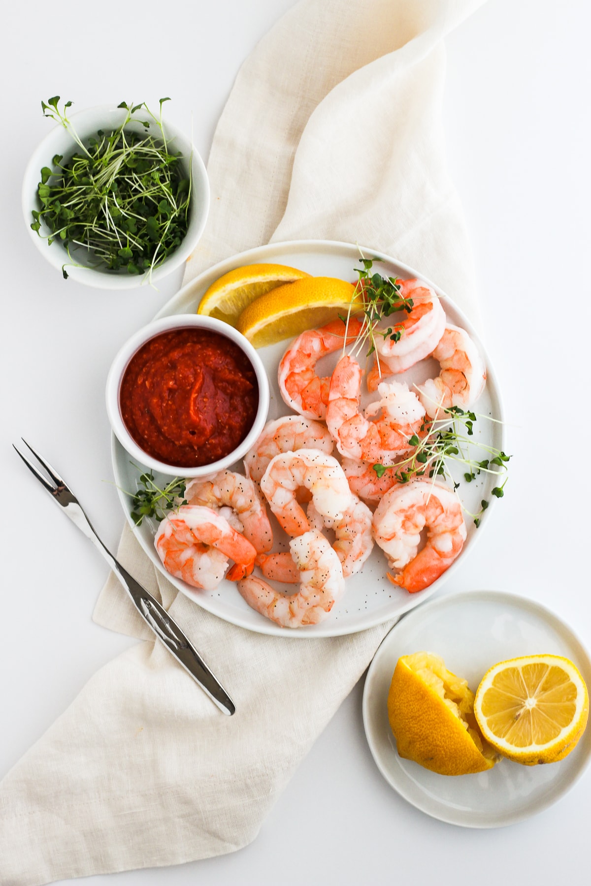 Plate of whole30 shrimp cocktail sauce with shrimp and lemon slices. 