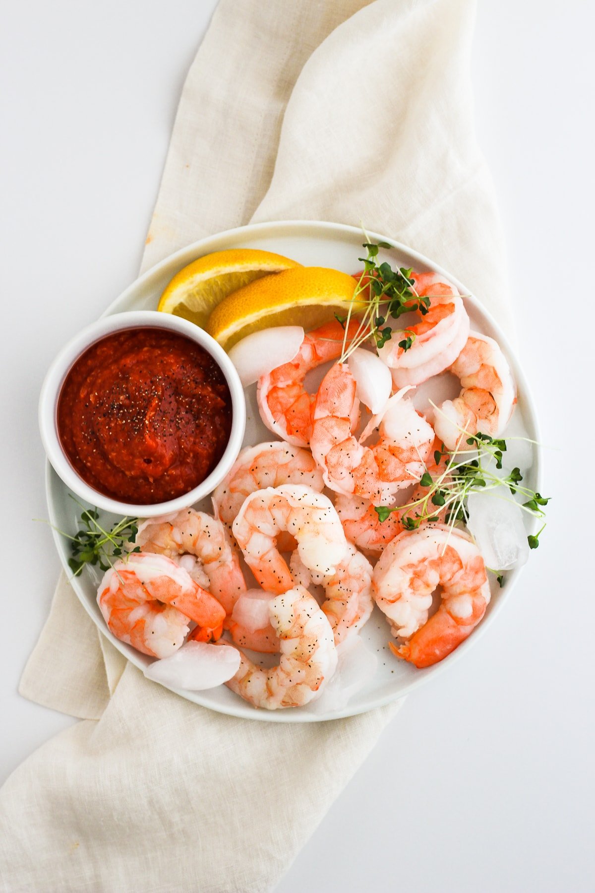 Plate of whole30 shrimp cocktail sauce with shrimp and lemon slices. 