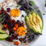 A plate of chorizo breakfast hash with slices of avocado.