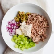 Tuna salad ingredients in a white bowl before being mixed.