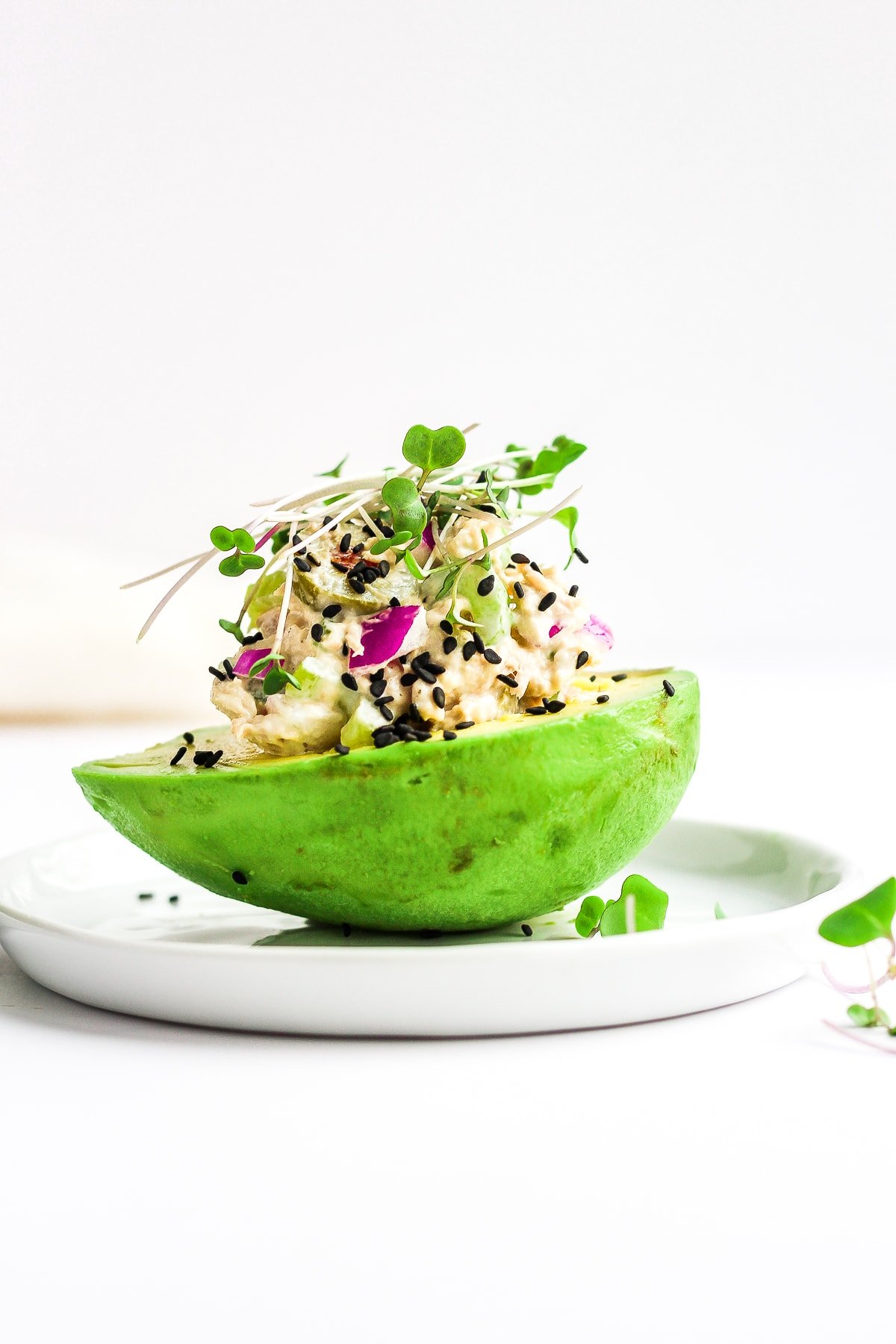 Healthy tuna salad sitting on top of a half of an avocado. 