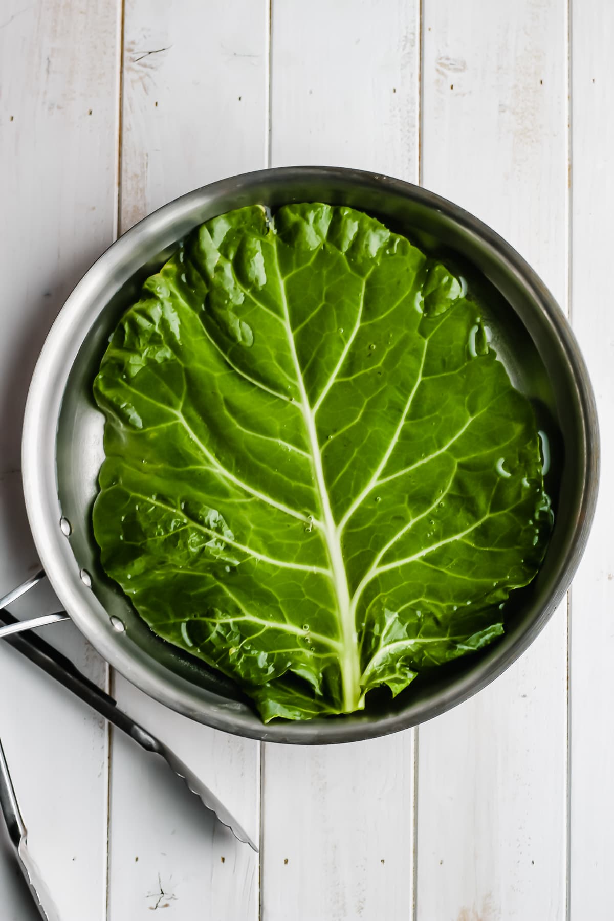 Collard leaf being blanched in boiling water.