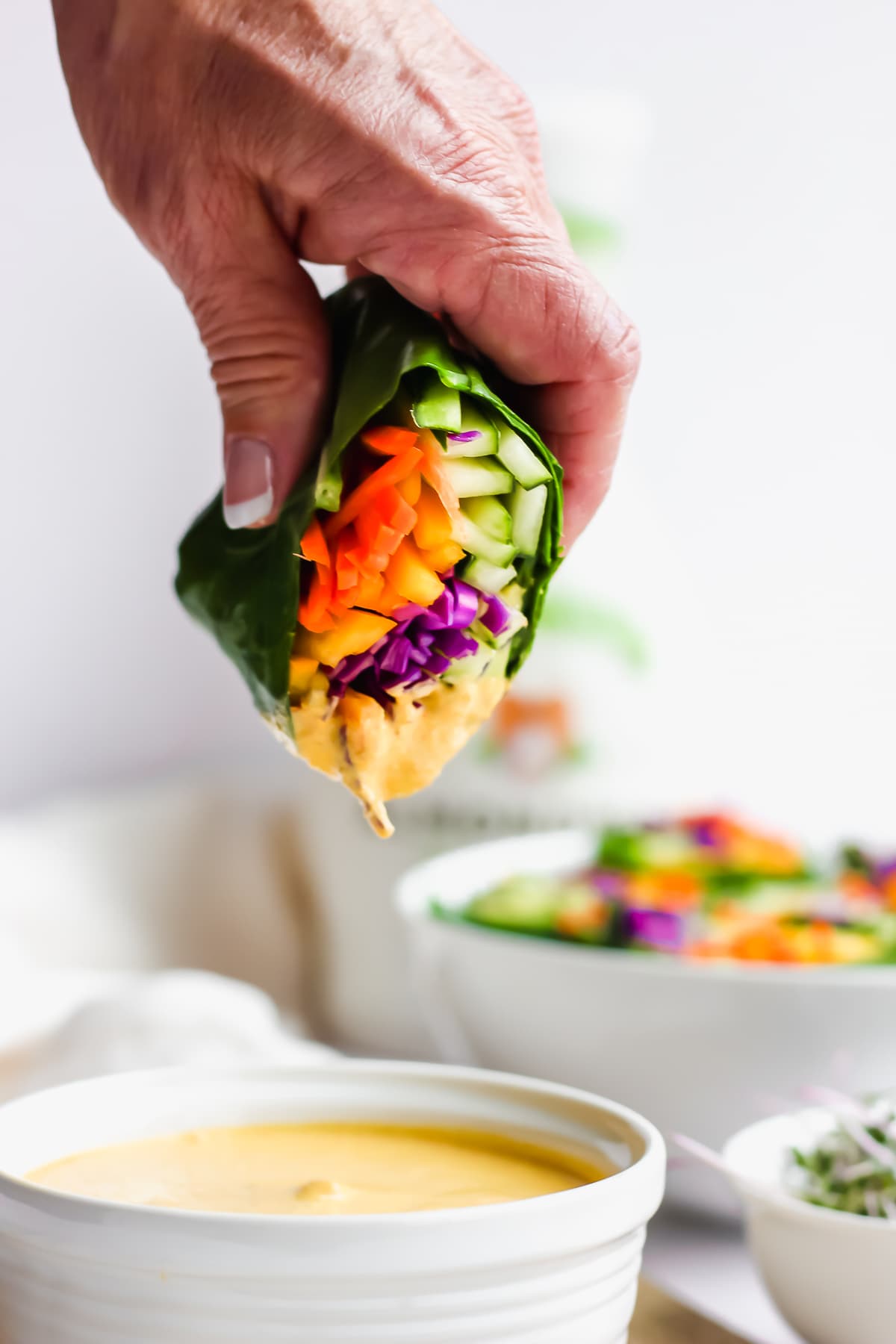 A veggie wrap being dipped in the tahini ginger dressing.