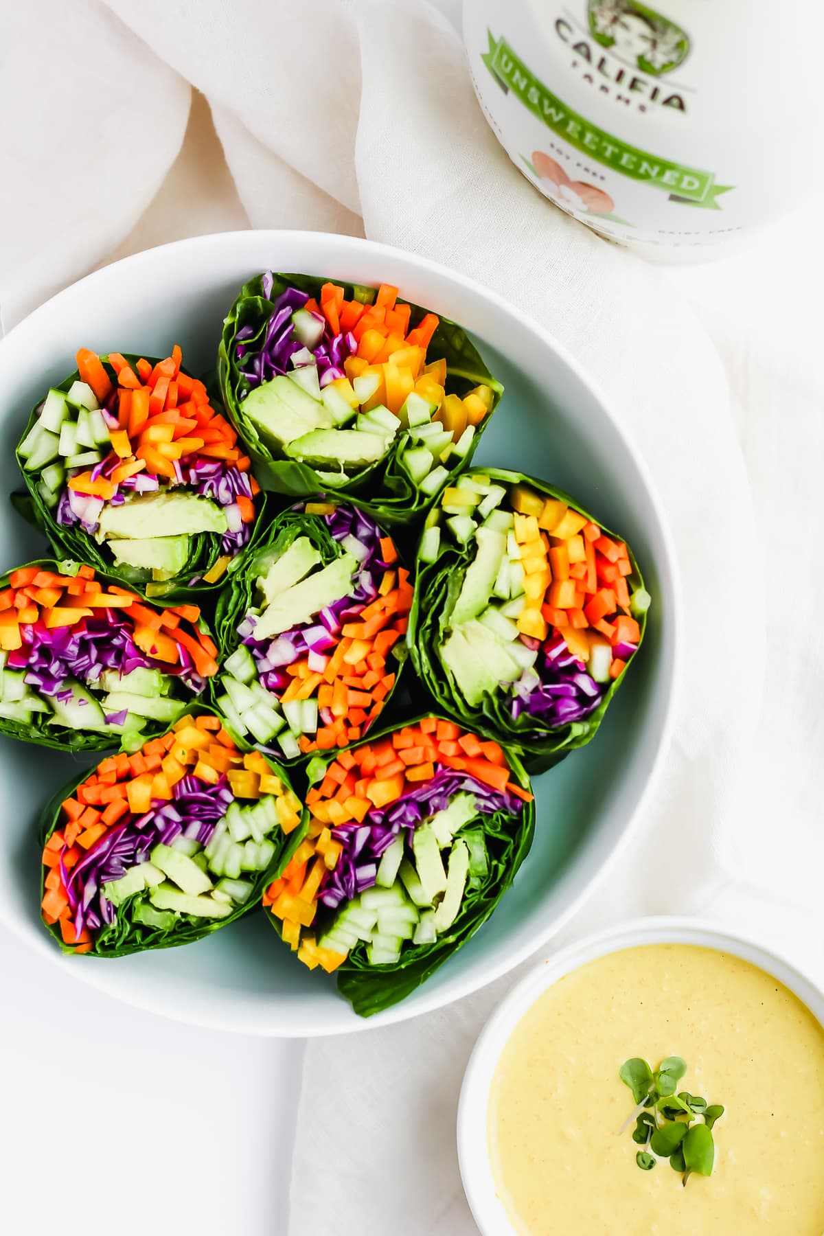 A large dish of veggie wrap halves and a side of the dressing.