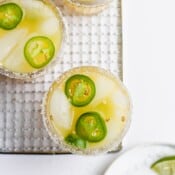 Jalapeño slices on top of two spicy jalapeño margarita mocktails.