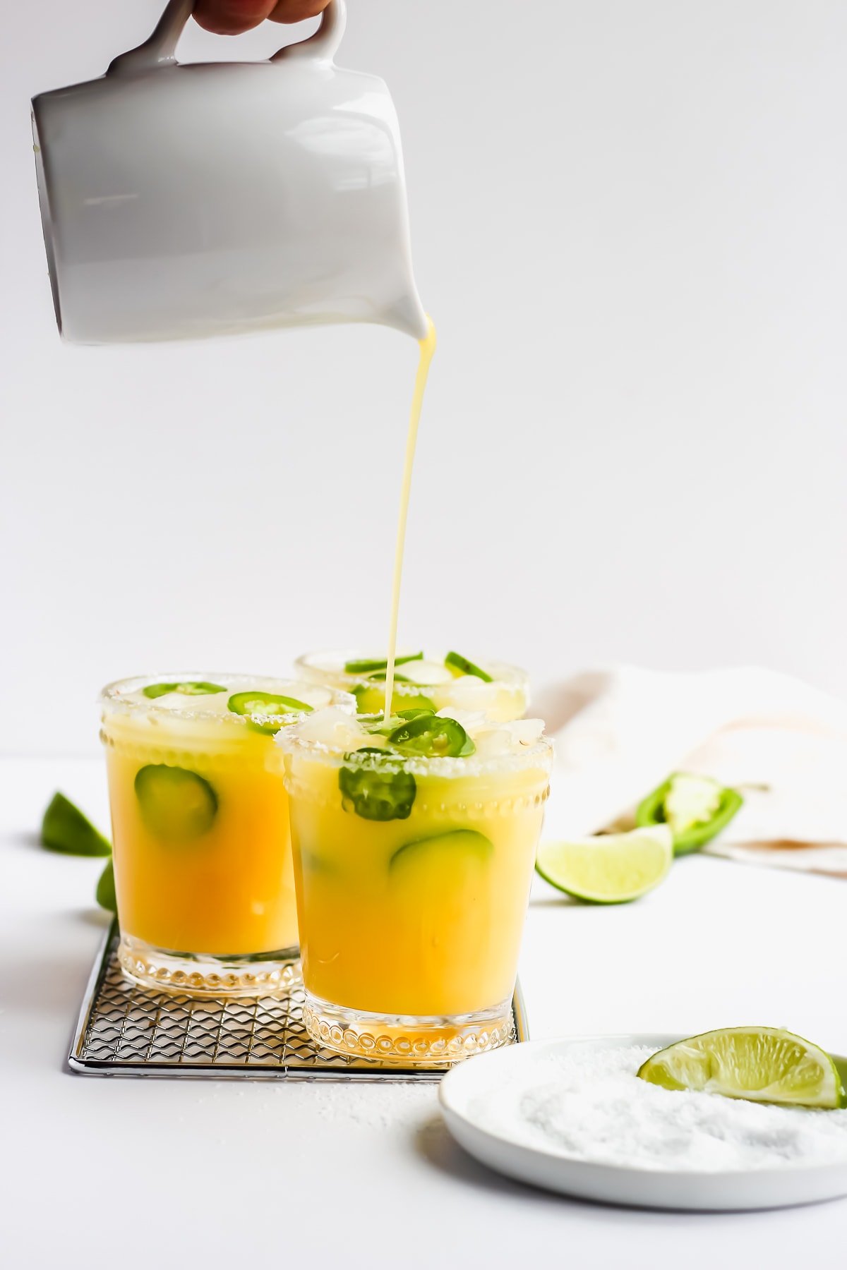 Someone pouring margarita mocktails into glasses.