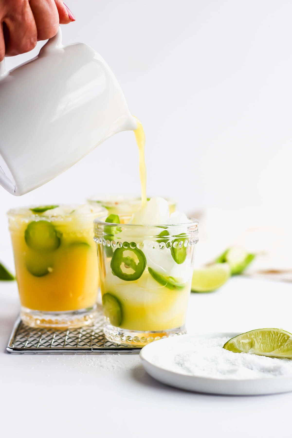 Someone pouring margarita mocktails into glasses. 