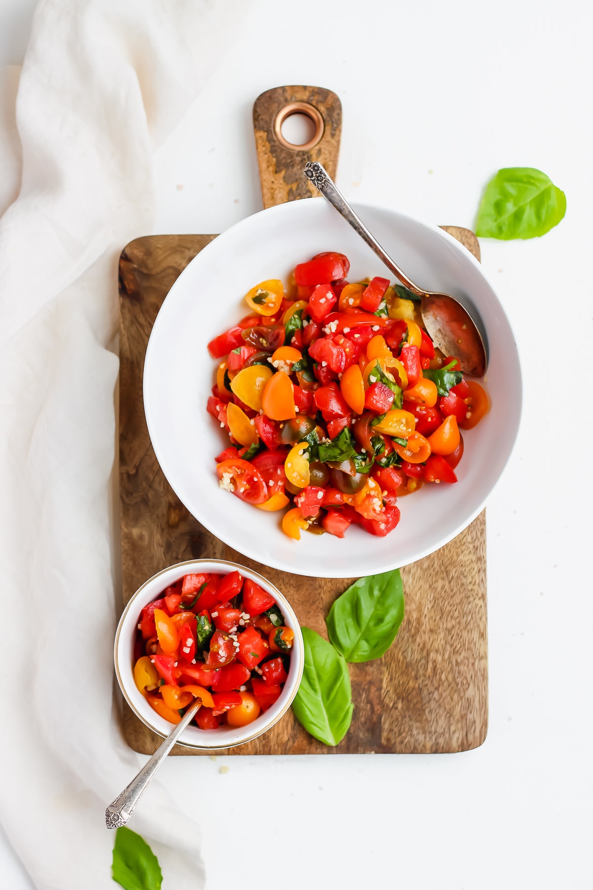 Chopped cherry tomatoes and roma tomatoes in a bowl combined with garlic, olive oil, and basil.