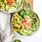 A bowl of shrimp and zoodles with a fork sticking out the side next to another bowl of shrimp and zoodles.