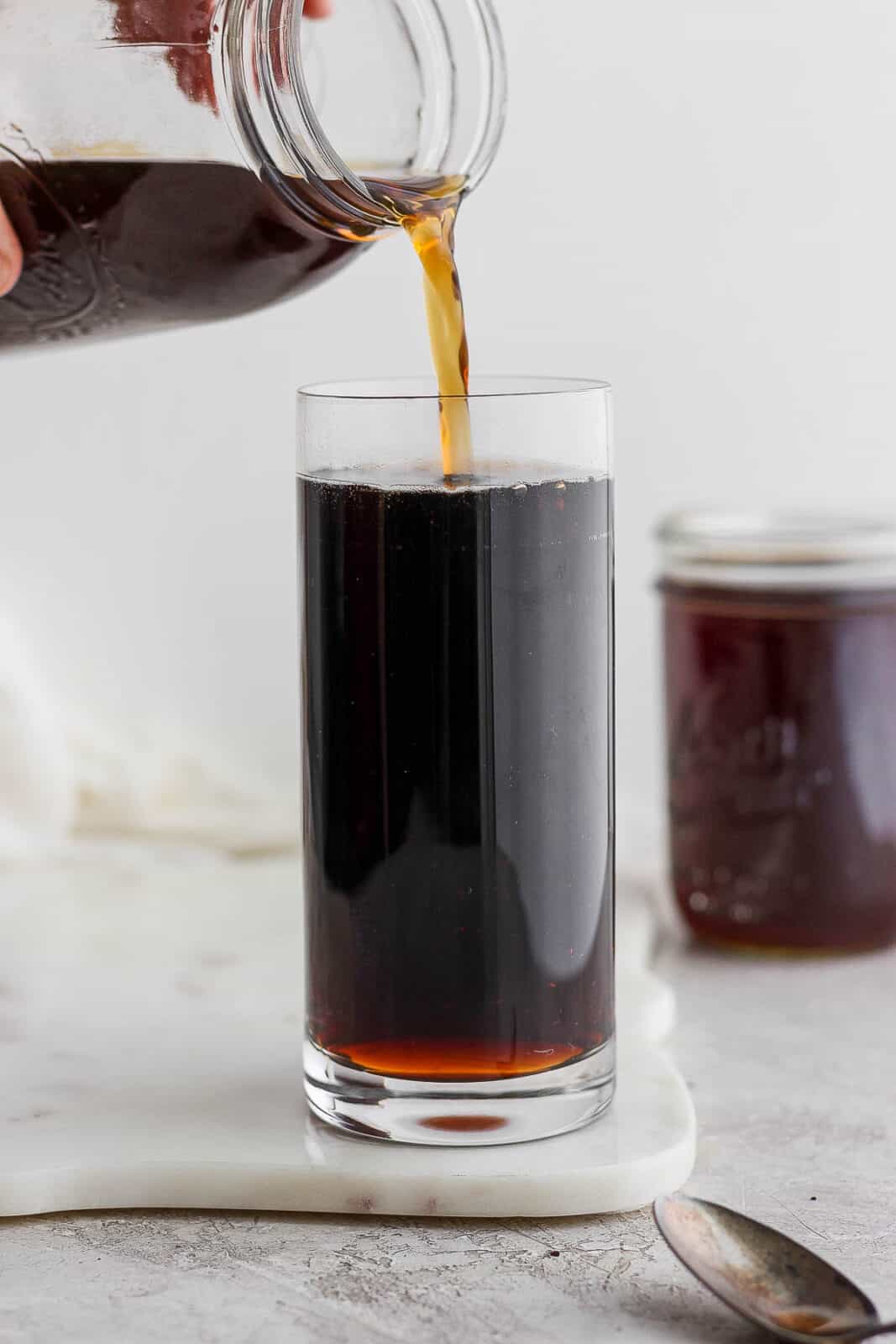 Someone pouring cold brew coffee into a glass. 