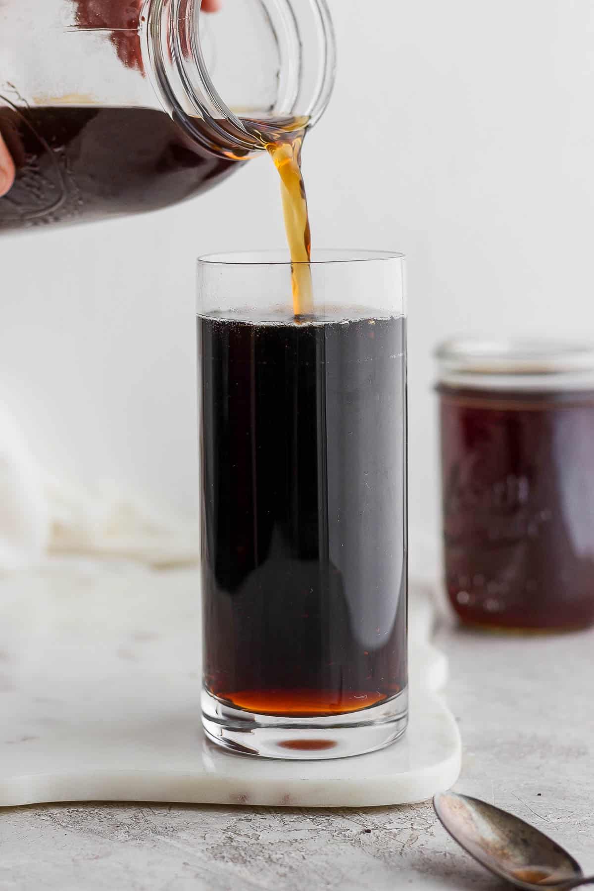 Someone pouring cold brew coffee into a glass. 