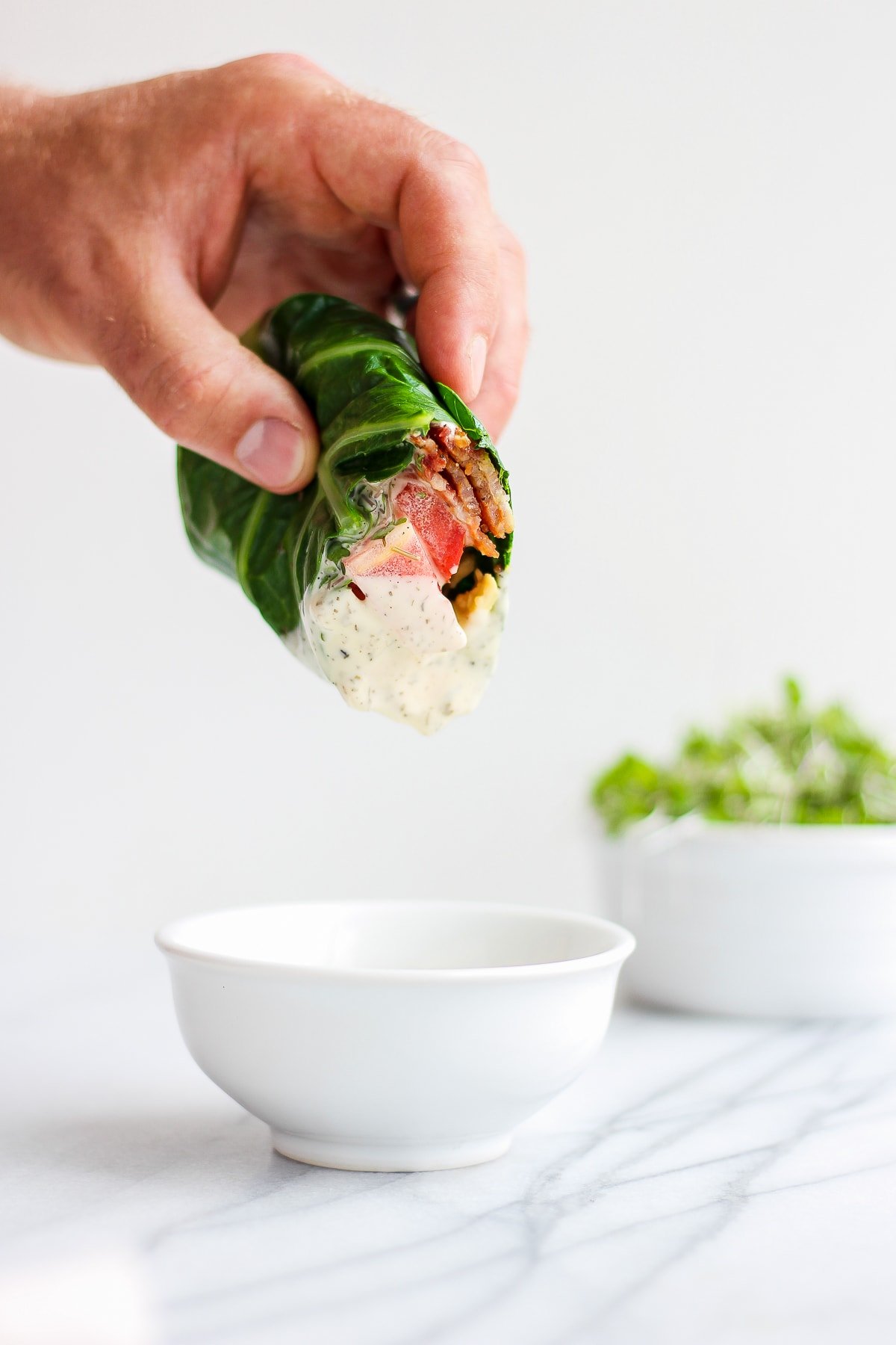 A wrap being dipped into a small dish of ranch dressing.