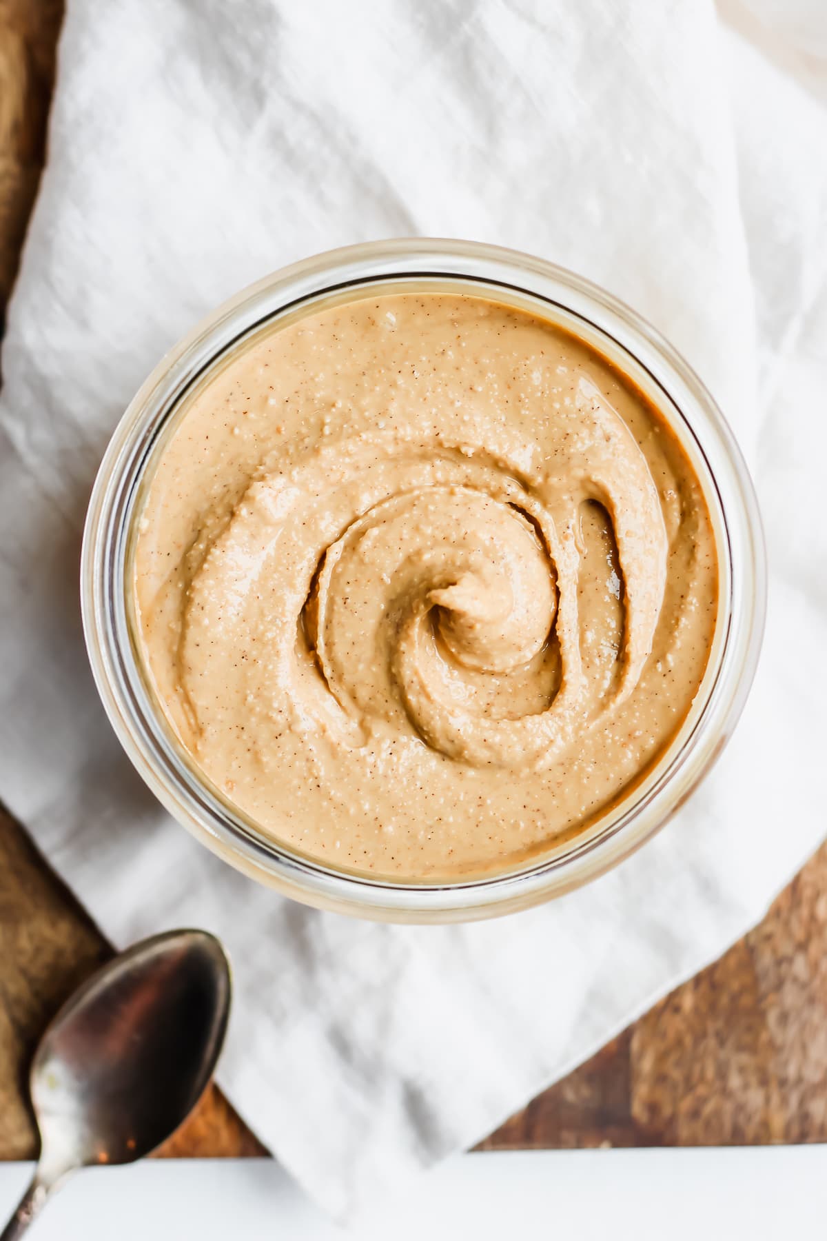 Jar of homemade cashew butter on a wooden board. 