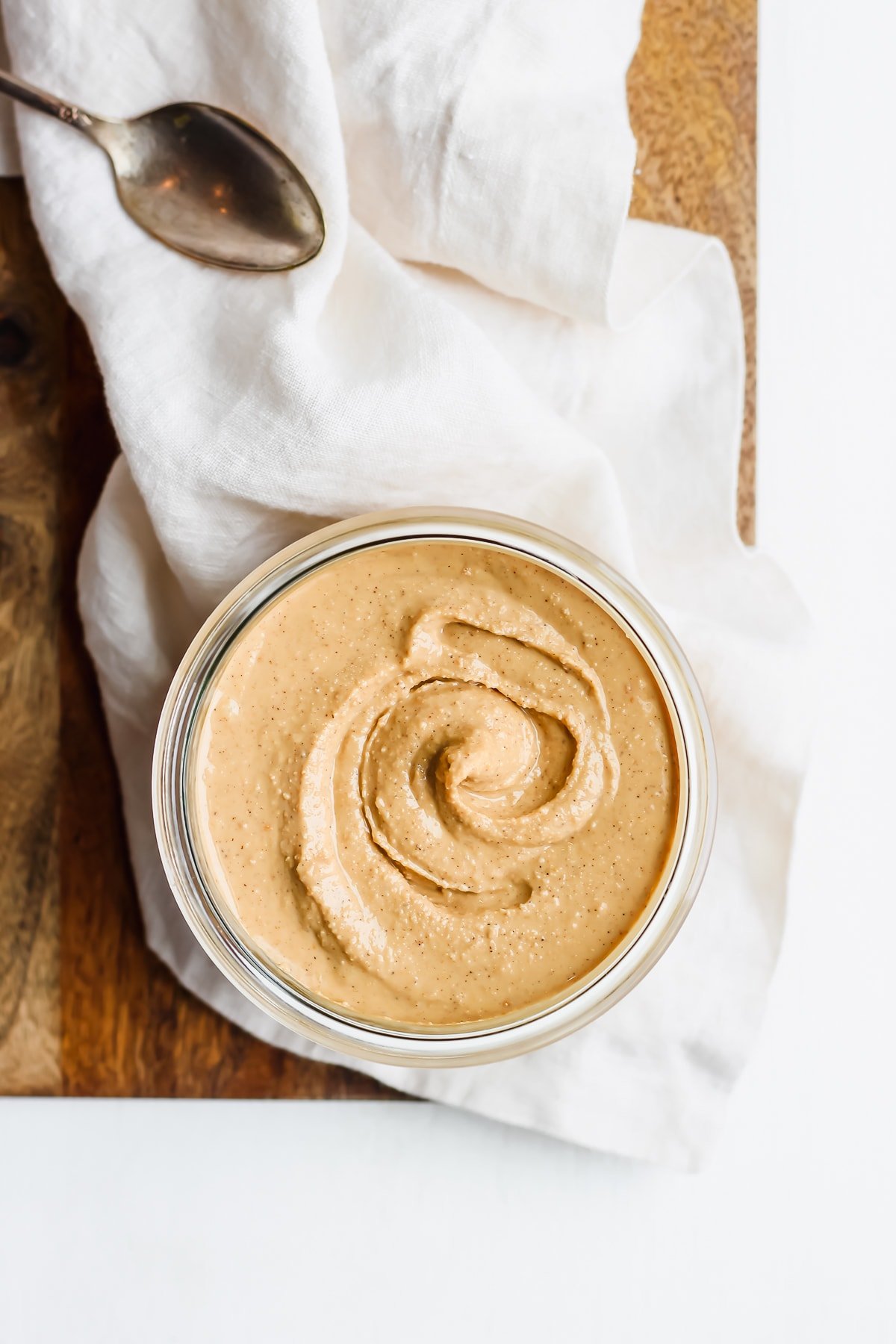 Jar of homemade cashew butter on a wooden board. 