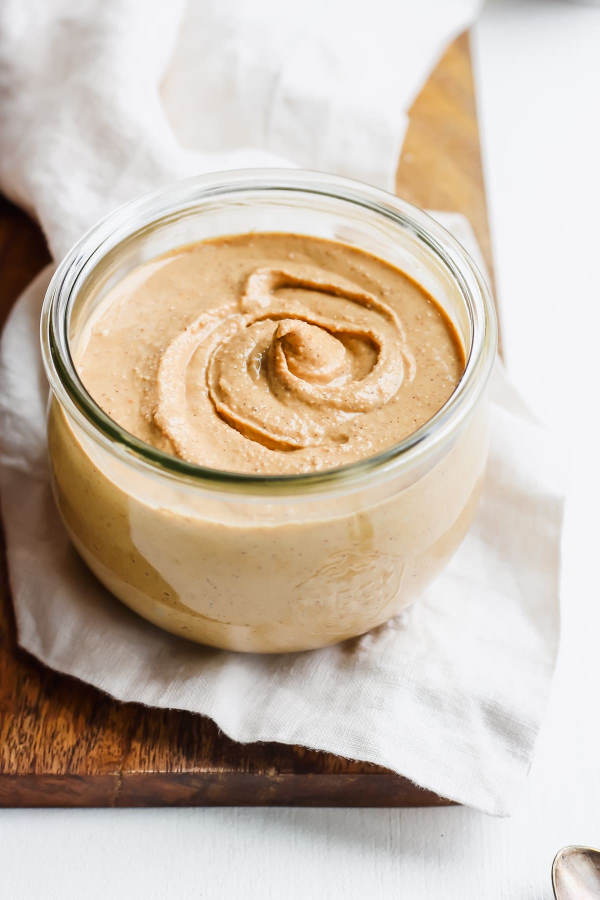 Jar of homemade cashew butter on a wooden board. 