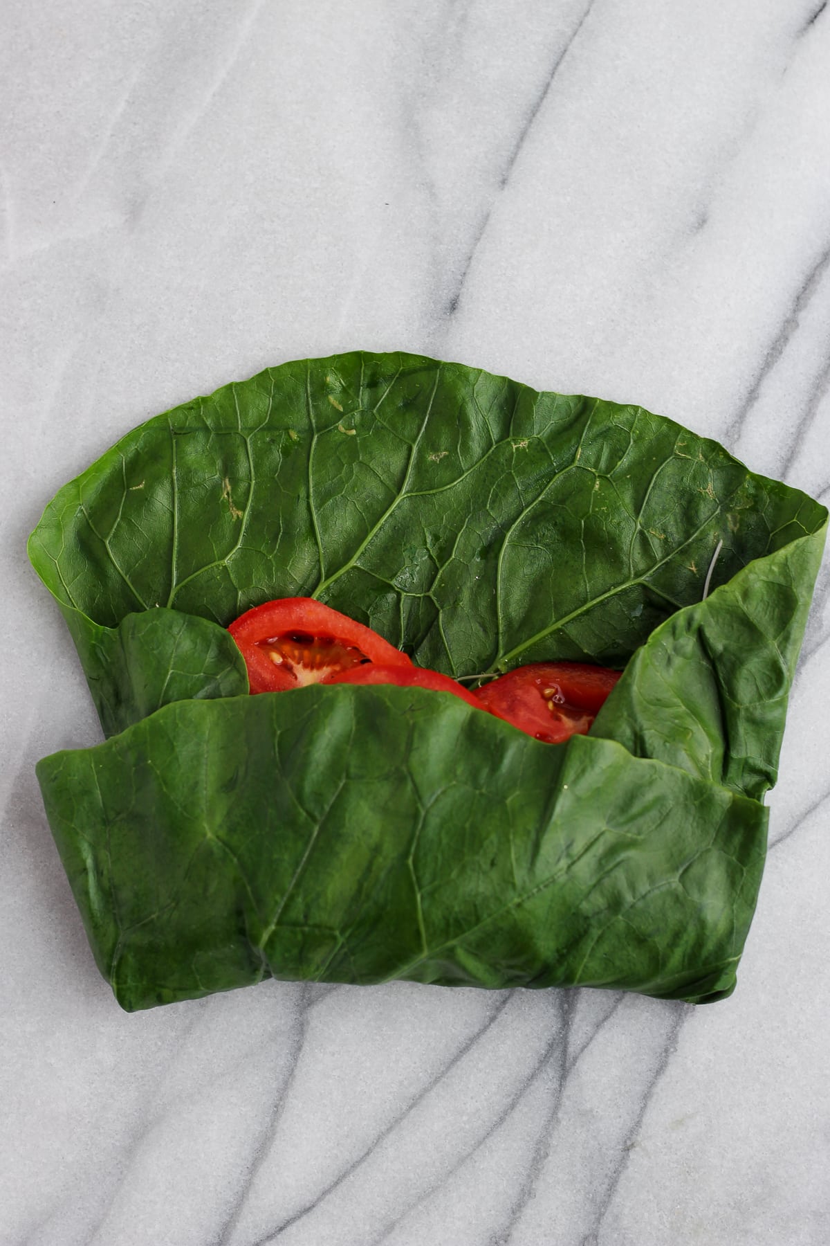 One side of the collard leaf folded over the filling ingredients.