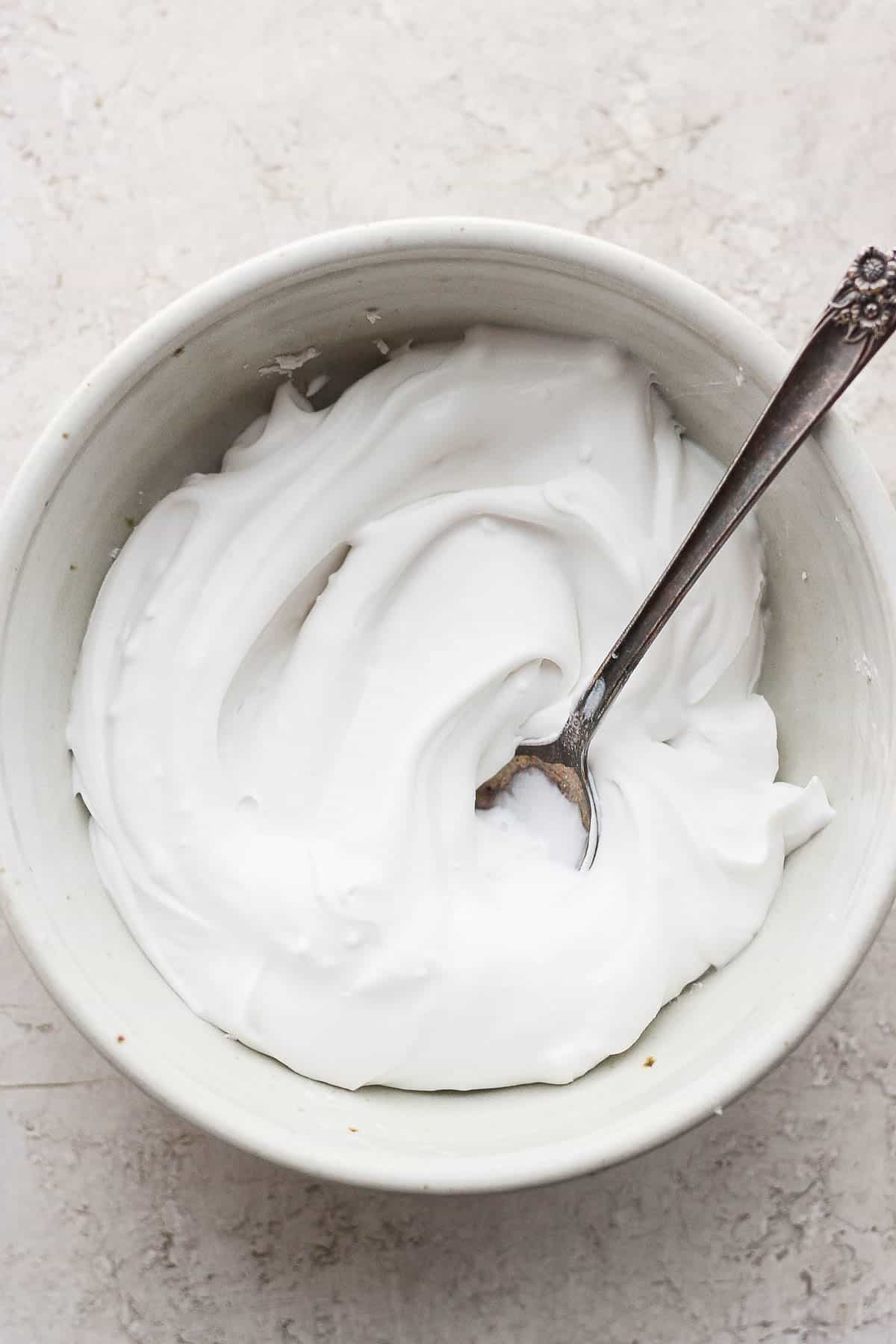 A bowl of dairy free sour cream with a spoon sticking out.