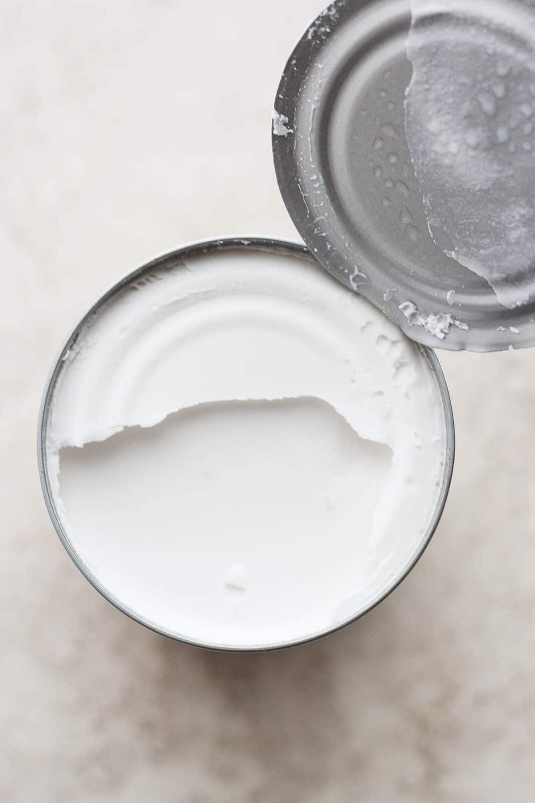 An opened can of coconut milk showing the coconut cream at the top. 