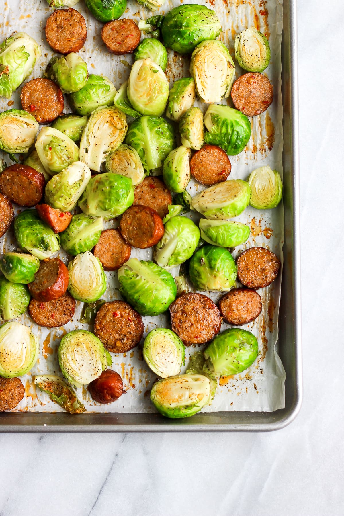Brussel sprouts and chorizo roasted on a parchment-lined baking sheet.