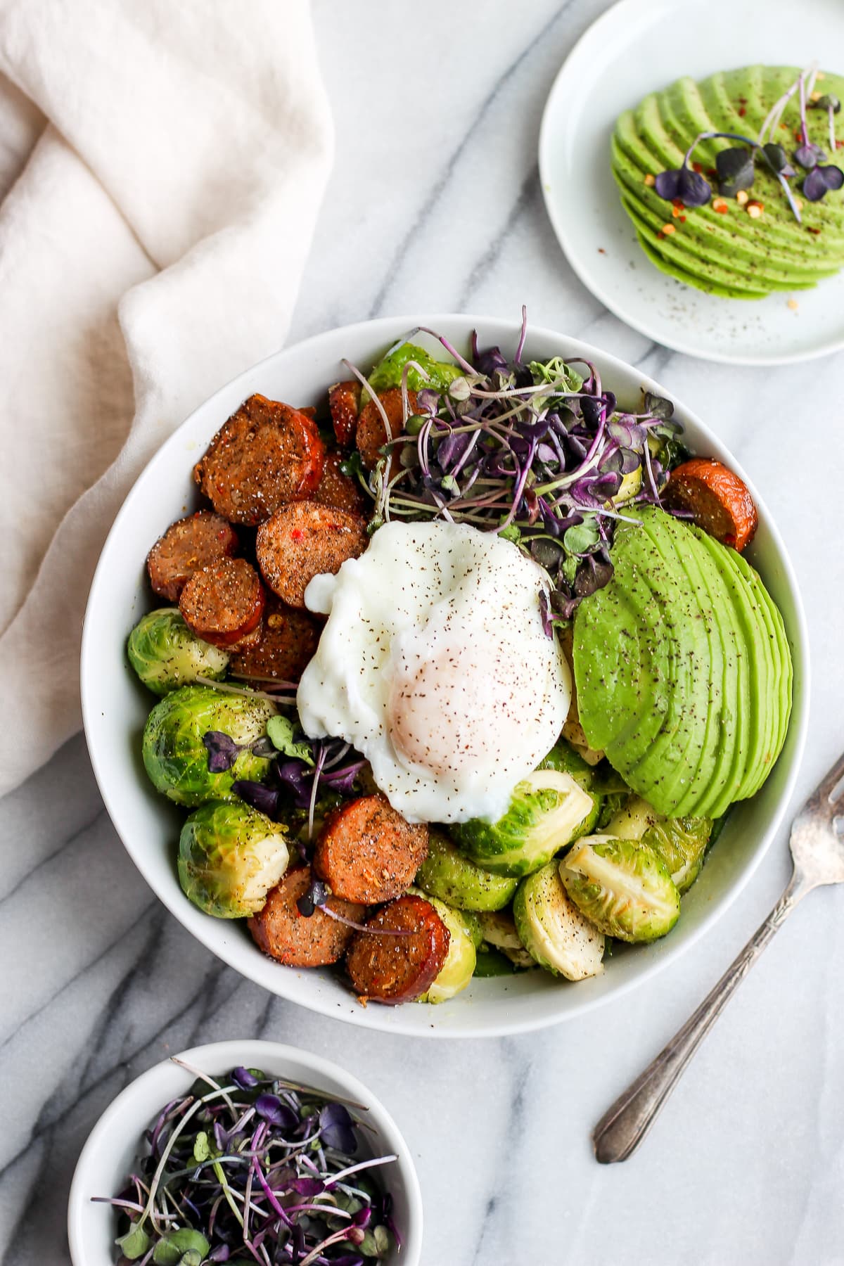 Chorizo sheet pan dinner in a bowl with a poached egg on top.