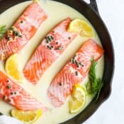 A cast iron skillet full of creamy lemon caper salmon.