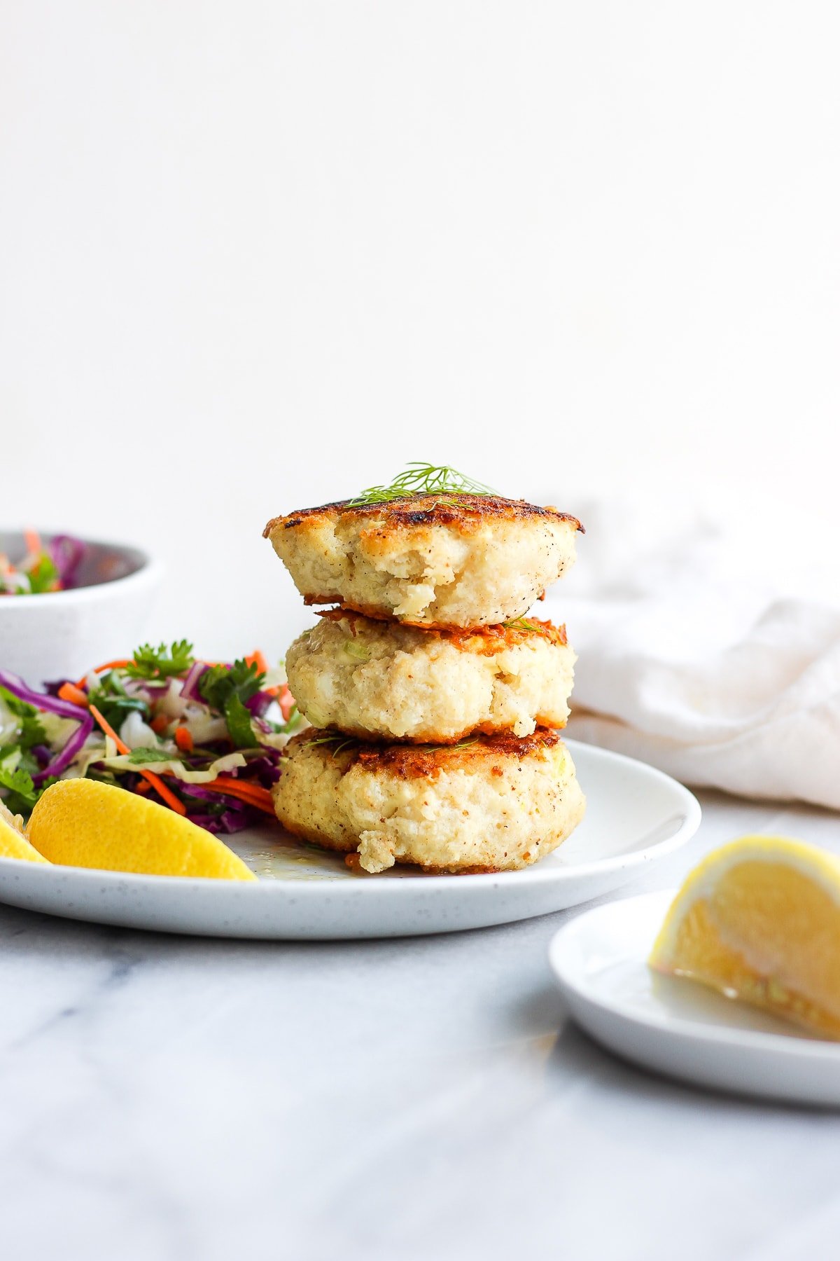 Cod cakes stacked on a white plate.