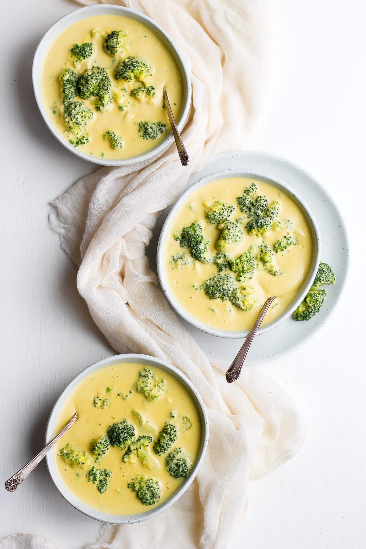 Bowls of broccoli cheese soup with spoons.