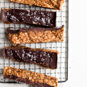 A wire rack full of six raw cashew chocolate breakfast bars.