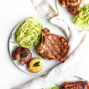 Three plates of grilled sumac pork chops with cooked potatoes and zoodles.