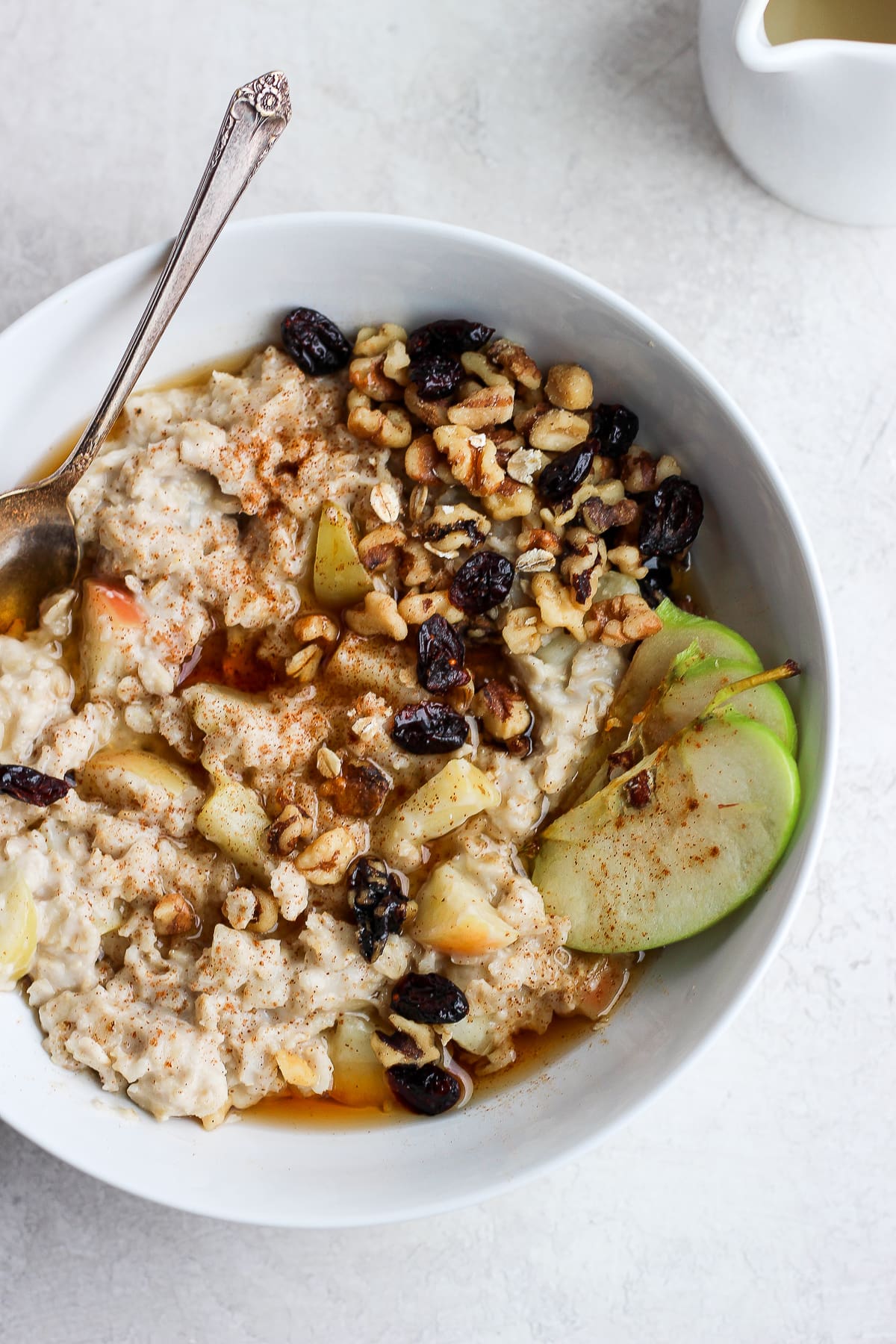 A bowl of apple pie oatmeal with a spoon.