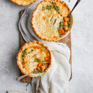 Three Fall harvest pot pies in bowls with spoons sticking out the sides.