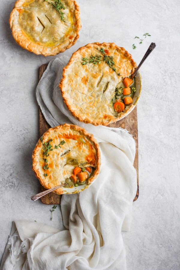 Three Fall harvest pot pies in bowls with spoons sticking out the sides.