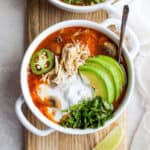 A bowl of white chicken chili with avocado, cilantro and sour cream.