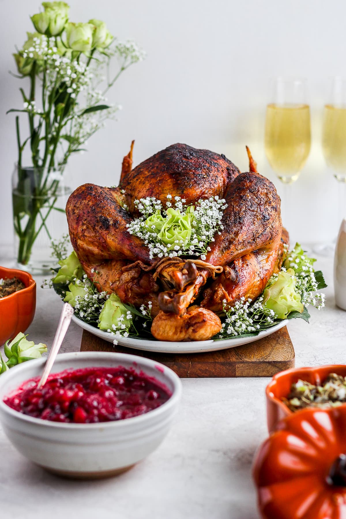 A roasted Thanksgiving turkey on a dinner table with side dishes.